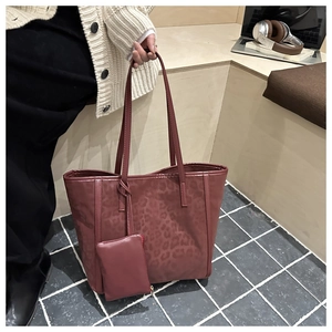 Dettaglio della borsa tote leopardata con mini pochette coordinata su sfondo di legno