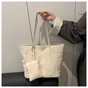 Dettaglio borsa tote in ecopelle color crema con cuciture verticali e mini borsa coordinata