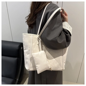Dettaglio della borsa tote crema con pochette coordinata indossata sulla spalla