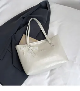 Dettaglio della borsa tote crema con pelle martellata e fiocco in pizzo con perle