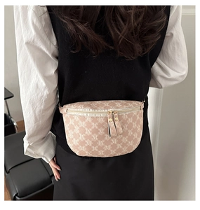 Detail of cross-body chest bag featuring M-pattern monogram and double zipper closure