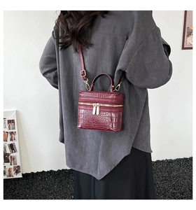Detail view of burgundy crocodile pattern mini handbag with handle and shoulder strap