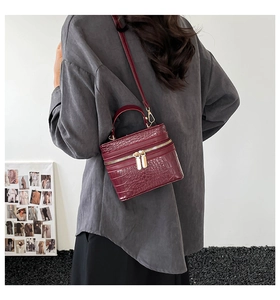 Side view of a vintage burgundy box bag with crocodile texture and golden zippers