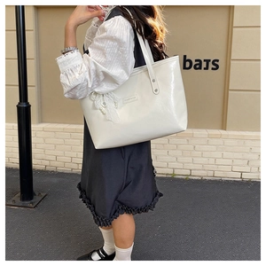 Borsa tote bianca lucida con pizzo e fiocco di perle mostrata in stile street outdoor