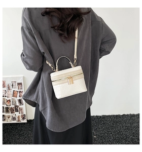 Rear view of model carrying a white crocodile pattern box bag with gold metal hardware