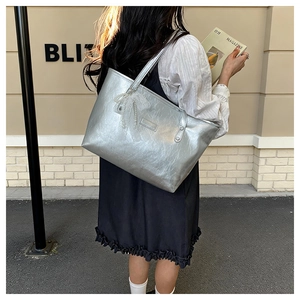 Dettaglio borsa shopper argento con fiocco in pizzo, perla e texture metallica stropicciata