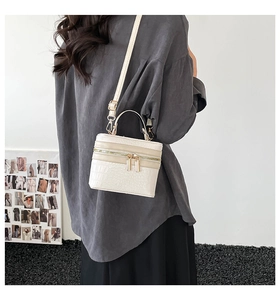 Detailed view of white crocodile pattern box bag with golden zippers worn crossbody by a model