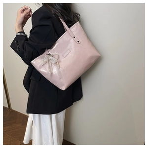 Dettaglio borsa a tracolla rosa con fiocco di pizzo, perle e logo Creative Cut inciso