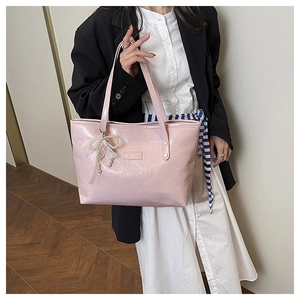 Dettaglio della borsa tote in vernice rosa con ciondolo a fiocco di pizzo e perle