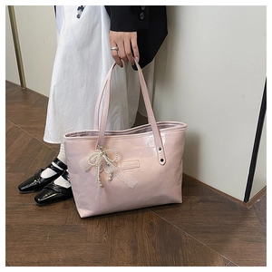 Dettaglio della borsa tote in vernice rosa con fiocco in pizzo bianco e ciondolo di perle