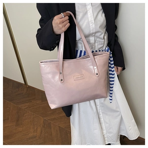Dettaglio della borsa tote in vernice rosa con etichetta Creative Cat e rivetti in metallo