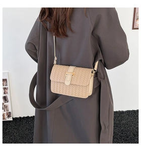 Dettaglio borsa a tracolla intrecciata beige con fibbia dorata su trench grigio