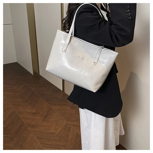Borsa tote bianca in ecopelle lucida con trama vintage indossata da una modella