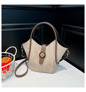 Detailed shot of cream pleated bucket bag with brown handles and golden metal twist lock