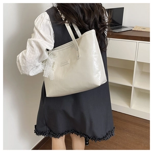 Dettaglio borsa tote bianco crema con elegante fiocco in pizzo perla e pelle lucida
