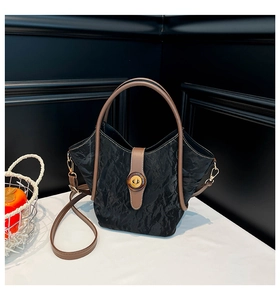 Close-up of black pleated texture bucket bag with retro amber ring and gold twist lock