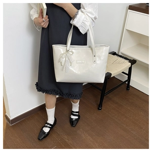 Dettaglio borsa tote in ecopelle bianca con fiocco di pizzo, perle e logo metallico
