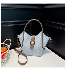 Detail of grey pleated bucket bag with brown leather handles and gold swivel lock