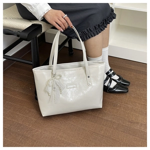 Dettaglio della borsa tote bianco crema con ecopelle ruvida e ciondolo di perle