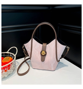 Detailed view of pink textured bucket bag with brown contrast trim and metal twist lock