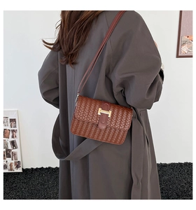 Vista posteriore della modella con borsa a tracolla in pelle intrecciata marrone e fibbia