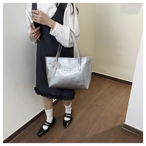 Dettaglio borsa tote argento metallizzato con texture stropicciata e fiocco di perle