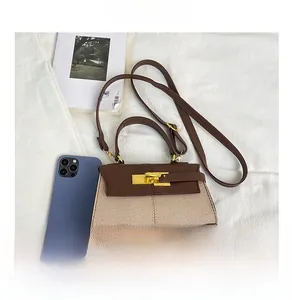 Dettaglio della mini borsa in pelle marrone e tela con chiusura dorata e smartphone