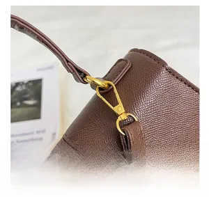 Dettaglio dei connettori metallici dorati e della pelle martellata marrone sulla borsa