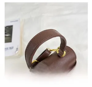 Dettaglio del manico in pelle marrone con fibbia dorata e cuciture precise