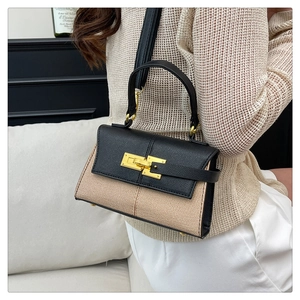 Dettaglio borsa a trapezio con patchwork in paglia beige, pelle nera e chiusura dorata