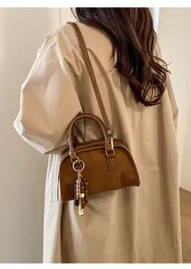 Dettaglio borsa vintage in pelle marrone con patchwork scamosciato e ciondolo decorativo