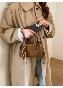 Dettaglio borsa a mano vintage marrone con perline decorative portata da una modella