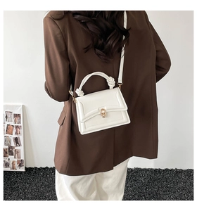 Piccola borsa bianca in pelle con fibbia dorata a U indossata da una modella esterna