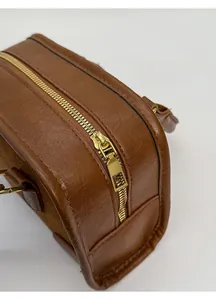 Dettaglio di borsa a tracolla vintage marrone con pelle PU e cerniera in metallo dorato