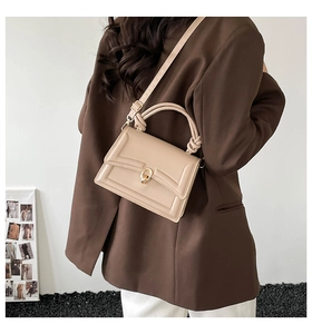 Dettaglio della borsa squadrata beige con chiusura a scatto dorata e tracolla