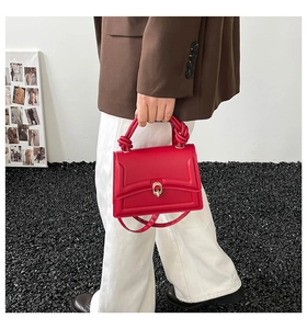 Dettaglio borsa rossa con manico a nodo artistico e chiusura dorata ovale elegante