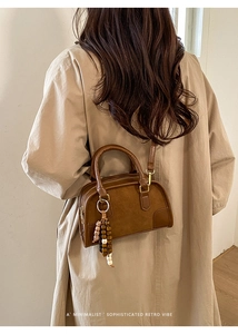 Borsa a tracolla vintage marrone opaca con charm in legno indossata dalla modella