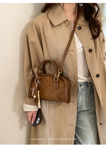 Borsa boston vintage marrone con ciondolo in legno indossata con un trench chic