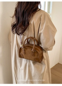Borsa Boston retrò marrone in pelle mista indossata da una modella in un ambiente minimal