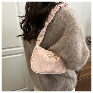 Détail du sac croissant rose clair avec nœud doré et texture plissée élégante