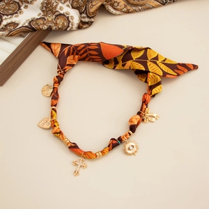 Close-up of heart and butterfly charms on autumn-toned leaf print satin necklace