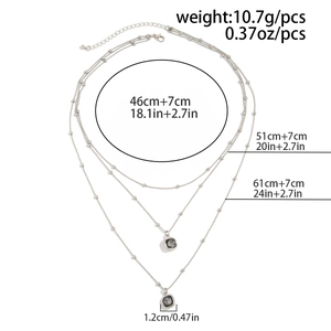 Three-layer layered necklace detail with silver-tone chains and gray stone pendants