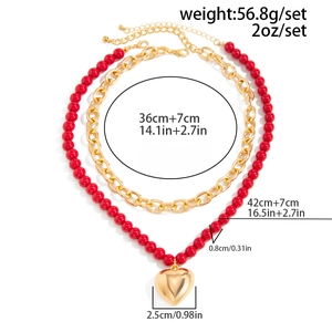 Detail view of layered gold chain and red bead heart necklace with size and weight specs