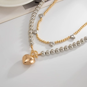 Detail of layered gold and silver beaded necklace with large heart pendant and OT clasp