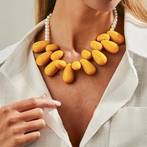 Collana con grandi perle in resina gialla e finte perle su una camicia di lino