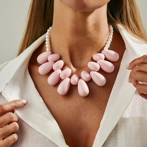 Collana con pendente a goccia in resina rosa e perle indossata da modella in camicia bianca