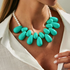 Collana con grandi ciondoli a goccia turchese e perle bianche su camicia di lino