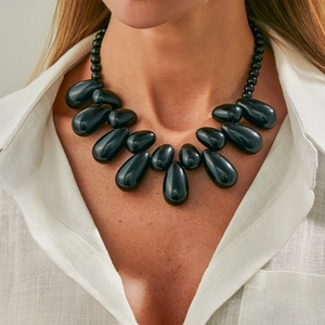 Collana boho con ciondolo a goccia in resina nera e perline lucide su sfondo bianco