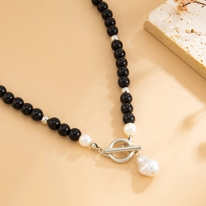 Dettaglio della collana con perle nere, chiusura a T e ciondolo con perla barocca