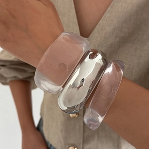 Three-piece set of transparent resin and polished silver bangles on a female model